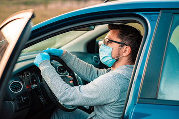 Young man using hand sanitizer or alcohol gel for washing hands in the car. Driver in a protective mask and gloves. Coronavirus pandemic. Quarantine.
