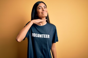 Young beautiful hispanic woman wearing volunteer t-shirt as social charity moral cutting throat with hand as knife, threaten aggression with furious violence