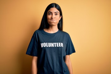 Young beautiful hispanic woman wearing volunteer t-shirt as social charity moral puffing cheeks with funny face. Mouth inflated with air, crazy expression.