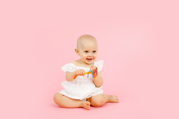 Little cute baby girl 1 years old wearing white summer dress isolated on pastel pink wall background, children studio portrait. Mother's Day, love family, parenthood childhood concept