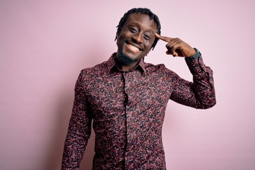 Young handsome african american man wearing casual shirt standing over pink background Smiling...