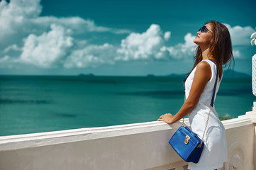 Elegant beautiful woman in white dress with handbag and sunglasses
