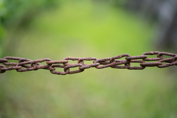 Old rusty iron chain, on a green background. Restriction of freedom