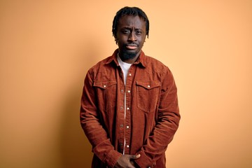 Young handsome african american man wearing casual jacket standing over yellow background skeptic and nervous, frowning upset because of problem. Negative person.