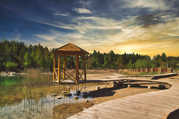A turquoise lake in the midst of a canyon. Travel and rest concept. A house by the lake, a wooden footbridge going deep into the turquoise lake.