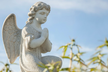 Ancient statue of  little angel against blue sky as symbol of guards for child.