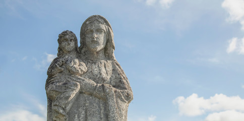 Fototapeta na wymiar Ancient stone statue of Virgin Mary with baby Jesus Christ