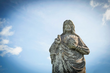 Fototapeta na wymiar Antique stone statue of Jesus Christ against blue sky