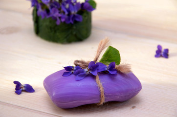 Obraz na płótnie Canvas purple soap and flowers violets on wooden background