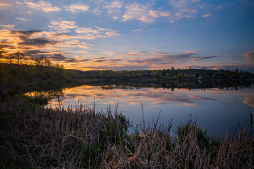 Amazing sunset view of scenic lake near medieval castle on the bank with reflection in the water and reeds on foreground. Svirzh, Ukraine. April 2020
