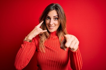 Young beautiful brunette woman wearing casual turtleneck sweater over red background smiling doing...