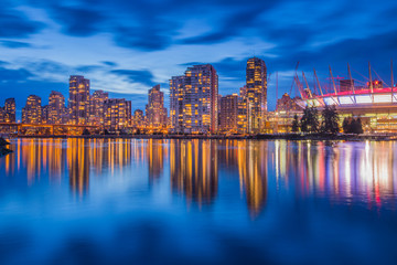 Fototapeta na wymiar Vancouver downtown architecture and boat with water reflections at dusk