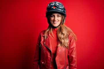 Young beautiful brunette motrocyclist woman wearing moto helmet over red background with a happy and cool smile on face. Lucky person.