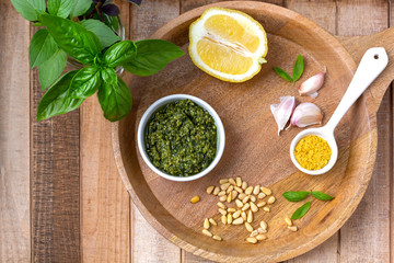 Top view of vegan basil pesto with ingredients on a wooden tray on wooden table top