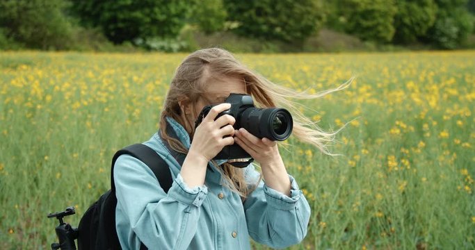 Pretty mature woman with blond hair in blue jacket taking pictures of beautiful nature surrounding her. Female photographer enjoying favorite hobby outdoors. Spring time concept.