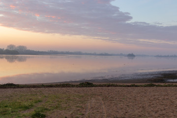 river landscape under a sunrise and clouds reflected in the water