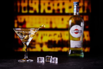 martini with green olives on a table in bar