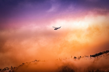 A helicopter fly's above a colorful mountain range in Kelowna BC