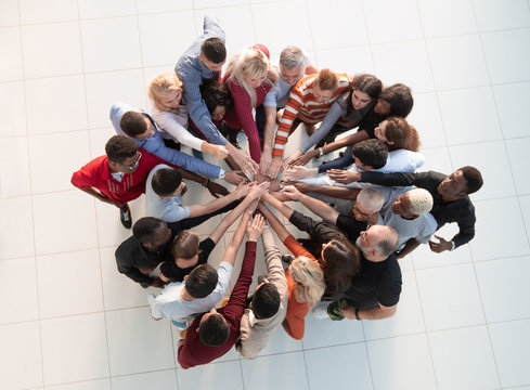 group of diverse people standing in a circle and joining their palms together.