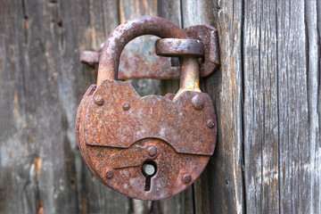 Old iron brown lock on a wooden gray rustic door.Close up.Selective focus.Concept of decoration,vintage design.