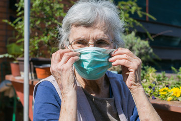 old woman putting on a face mask