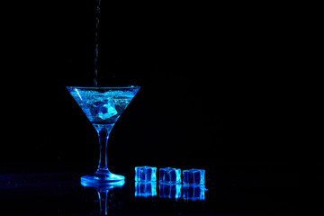 Martini cocktail drink splash with ice cubes in neon iridescent . Minimal night party life concept.