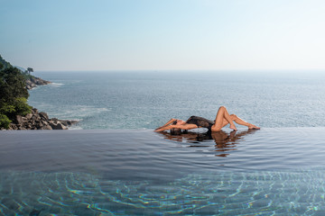 woman lie in infinity pool at sunrise