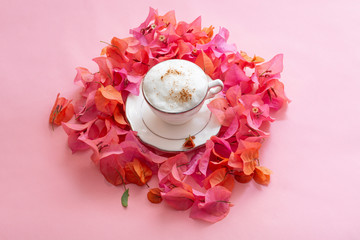 Café espumoso rodeado de buganvilias en fondo rosa
