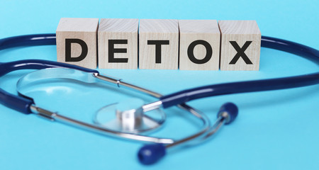 Detox word written on wood block on blue background. Medical concept.