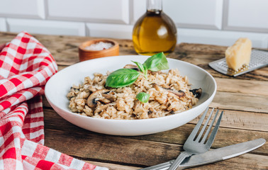 Homemade traditional Italian mushroom risotto on rustic wooden background. Classic Risotto with mushrooms served on a white plate