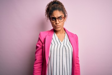 Beautiful african american businesswoman wearing jacket and glasses over pink background skeptic...