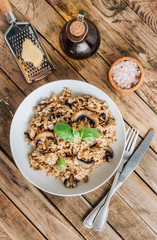 Homemade traditional Italian mushroom risotto on rustic wooden background. Classic Risotto with mushrooms served on a white plate