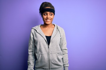 Young african american sportswoman doing sport wearing sportswear over purple background smiling looking to the side and staring away thinking.