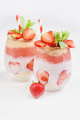 Glass of sweet delicious homemade layered smoothie dessert made from fruits and berries. delicious Strawberry banana milkshake, vegan raw food. Selective focus. Chia pudding with oatmeal