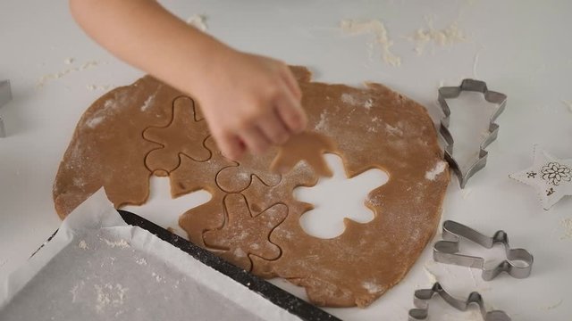 Child's hands making traditional Christmas cookies. Raw dough and cutters for holiday cookies on the table. Christmas cookies.