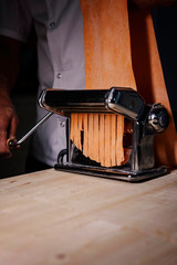 Chef prepearing fresh orange pasta with machine