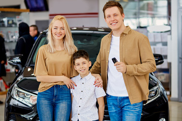 young caucasian family with child happy after getting keys from their new car in dealership, successful purchase without credit. cars, automobile, dealership concept