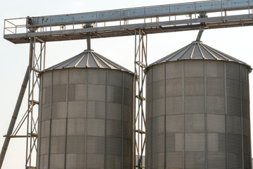 A large modern plant for the storage and processing of grain crops. view of the granary on a sunny day, barrels close-up. End of harvest season. Strategic grain reserve in the city center.