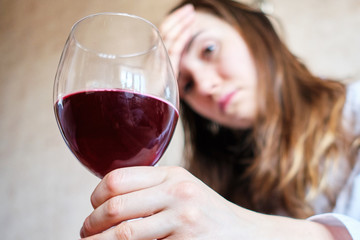 A woman is sitting on a sofa with a glass of wine