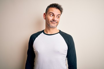 Young handsome man wearing casual t-shirt standing over isolated white background smiling looking to the side and staring away thinking.