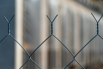 Metal mesh fence close-up. Abstract and Blurred focus. Construction site is not of focus behind the...