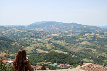 Woman viewing tuscany italy from the top of san marino social distancing herself
