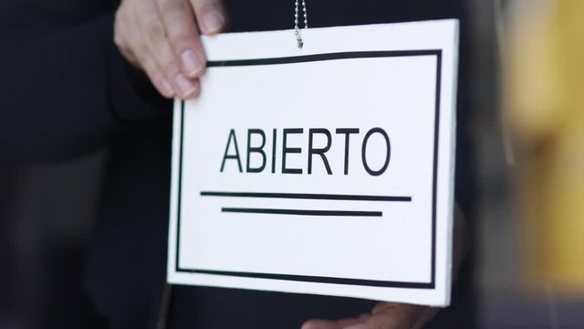 Propietaria de una peque&ntilde;a empresa gira el cartel para la reapertura del lugar despu&eacute;s de la cuarentena debido a covid-19. En M&eacute;xico