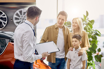 beautiful caucasian family have conversation with affable pleasant salesman in dealership, get consultation before purchase