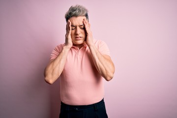 Young handsome modern man wearing casual pink t-shirt over isolated background with hand on head for pain in head because stress. Suffering migraine.