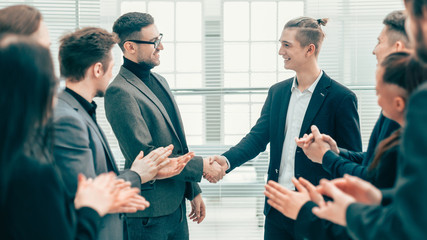 business partners shaking hands to the applause of the business team