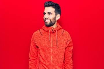 Young handsome man with beard wearing casual sweatshirt looking to side, relax profile pose with natural face and confident smile.