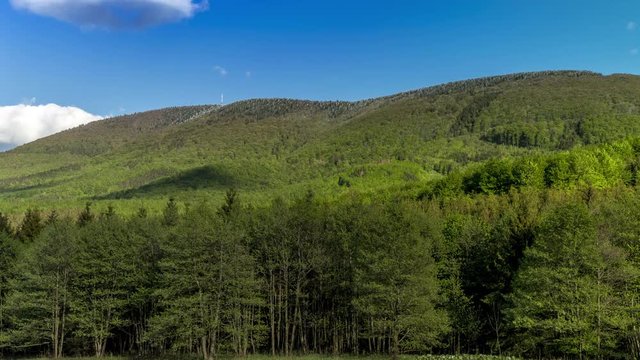 Timelapse of shadows and clouds moving on slopes of Radhost Hill overlooking a broadcast tower in a dense forest with moving shadows reflecting the sun from the advancing clouds Beskydy Park area.