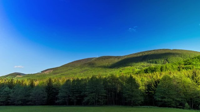 Timelapse of shadows and clouds moving on slopes of Radhost Hill overlooking a broadcast tower in a dense forest with moving shadows reflecting the sun from the advancing clouds Beskydy Park area.
