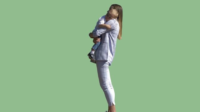 A young mother stands and holds her little son in her arms. Alpha channel background